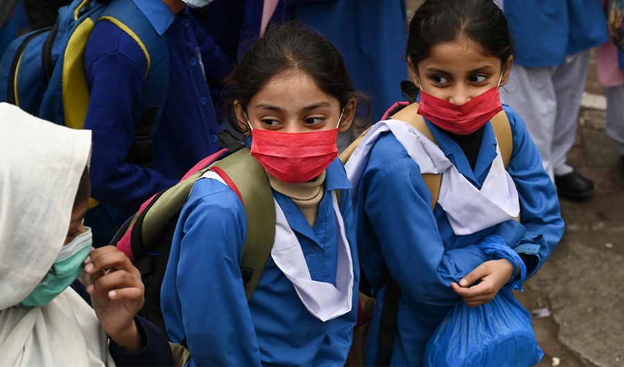 Students wearing facemasks gather outside the school as they prepare to return home after attending class, amid the Covid-19 coronavirus pandemic in Lahore on November 25, 2020. (AFP)