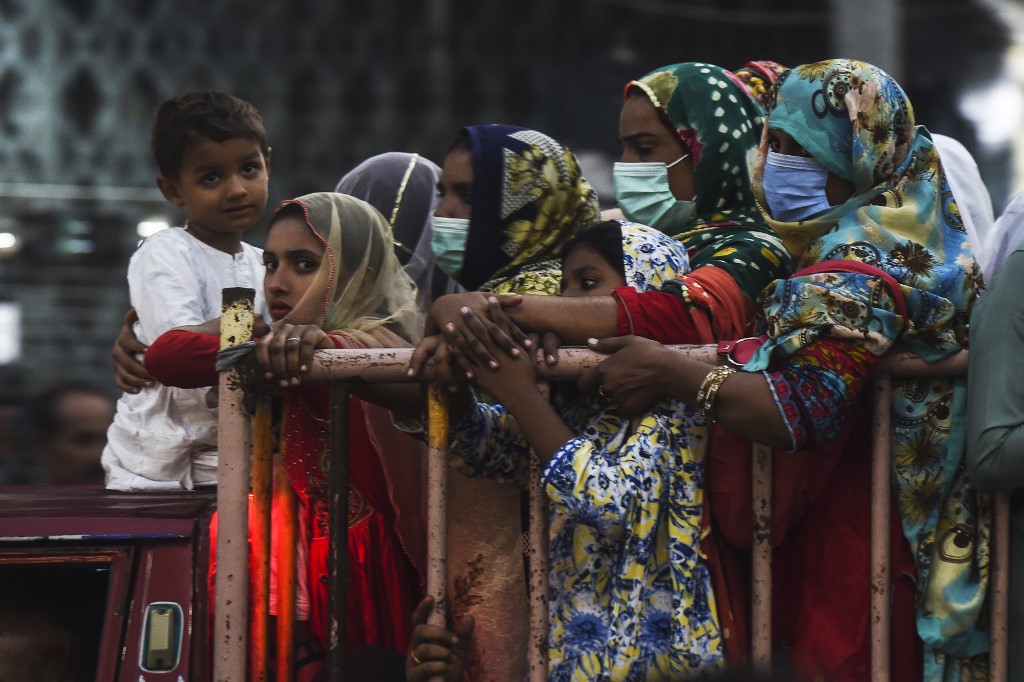 People wearing face masks as a preventive measure against the coronavirus ride at the back of a vehicle along a street, in Karachi on October 29, 2020. (AFP/File)