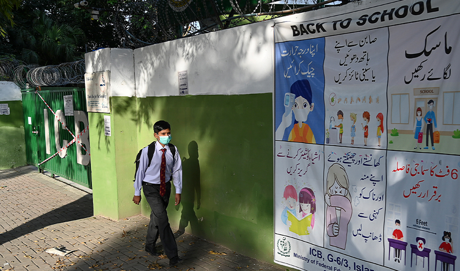 A student wearing a facemask leaves beside a closed school sealed by authorities as some teachers and students tested positive for the Covid-19 Coronavirus in Islamabad on October 5, 2020. (AFP)