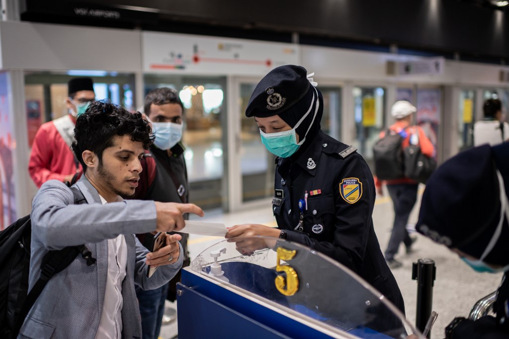 In this picture taken on February 14, 2020, security officers wearing protective face masks check travelers making their way to their boarding gates at the Kuala Lumpur International Airport in Kuala Lumpur, Malaysia. (AFP/File)