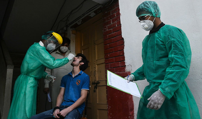 A health official wearing Personal Protective Equipment (PPE) takes a swab sample from a man during door to door a screening and testing for the COVID-19 coronavirus at a restricted area sealed by the authorities in Islamabad on June 29, 2020, as virus cases continue to rise. (AFP)