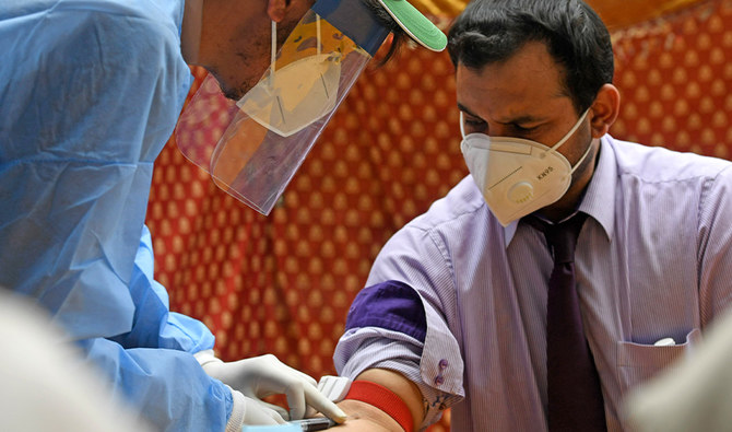 A health official wearing protective gear takes blood sample of a man at a drive-through screening and testing facility for the COVID-19 coronavirus, alongside a street in Islamabad on June 10, 2020. (AFP)