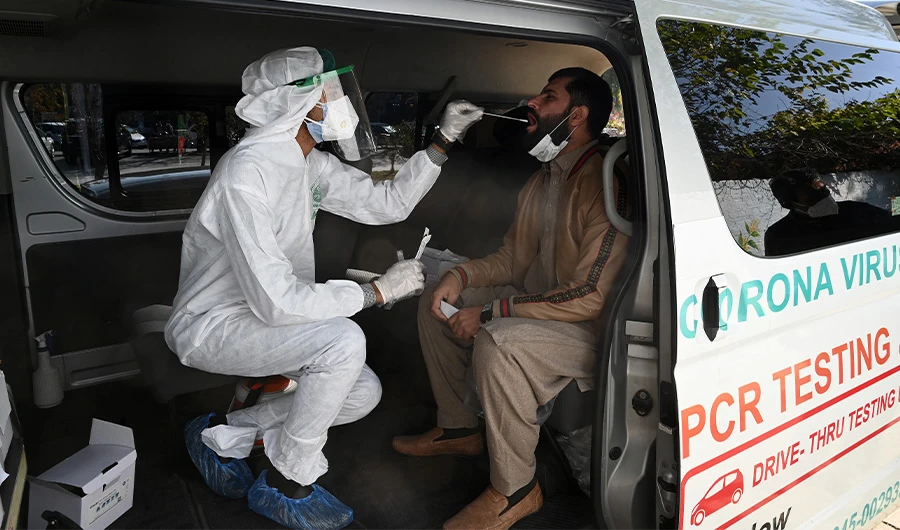 A health official collects a swab sample from a man to test for the Covid-19 coronavirus inside a van along the roadside in Islamabad on November 26, 2020. (AFP)