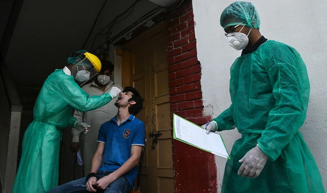A health official wearing Personal Protective Equipment (PPE) takes a swab sample from a man during door to door a screening and testing for the COVID-19 coronavirus at a restricted area sealed by the authorities in Islamabad on June 29, 2020, as virus cases continue to rise. (AFP)