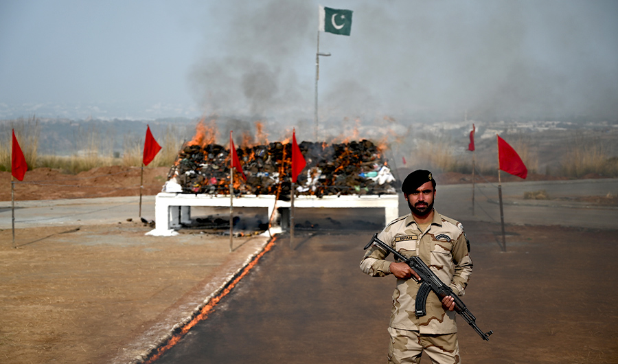 A soldier of the Anti-Narcotic Force (ANF) stands guard beside a burning pile of seized drugs by ANF on the outskirts of Islamabad on December 24, 2019. - Pakistani authorities torched tonnes of seized drugs, including heroin, hashish, cocaine, and opium at a ceremony attended by diplomats and anti-narcotics officials. (AFP Photo)