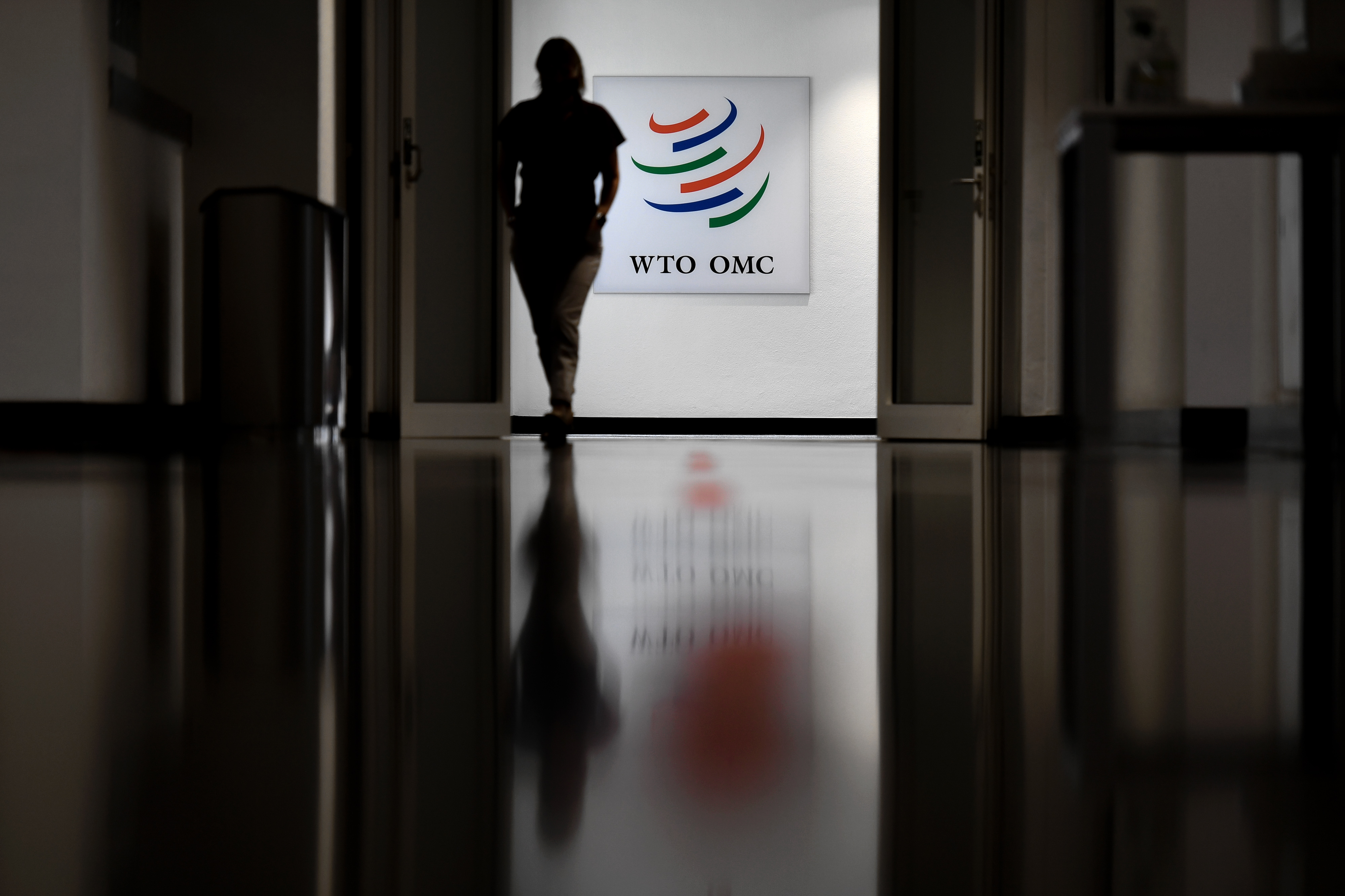 A woman walks past a sign of the World Trade Organization on July 15, 2020, in Geneva, during the hearing of candidate before the World Trade Organization 164 member states' representatives, as part of the application process to head the WTO as Director General. (AFP)