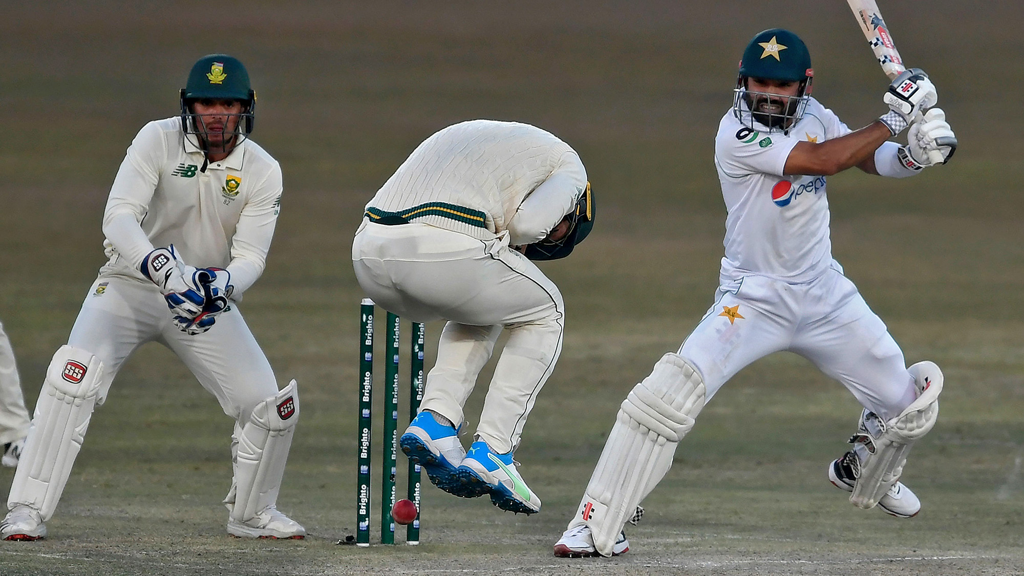 Pakistan's Mohammad Rizwan (R) plays a shot as South Africa's wicketkeeper captain Quinton de Kock (L) watches during the third day of the second Test cricket match between Pakistan and South Africa at the Rawalpindi Cricket Stadium in Rawalpindi on Feb. 6, 2021. (AFP)