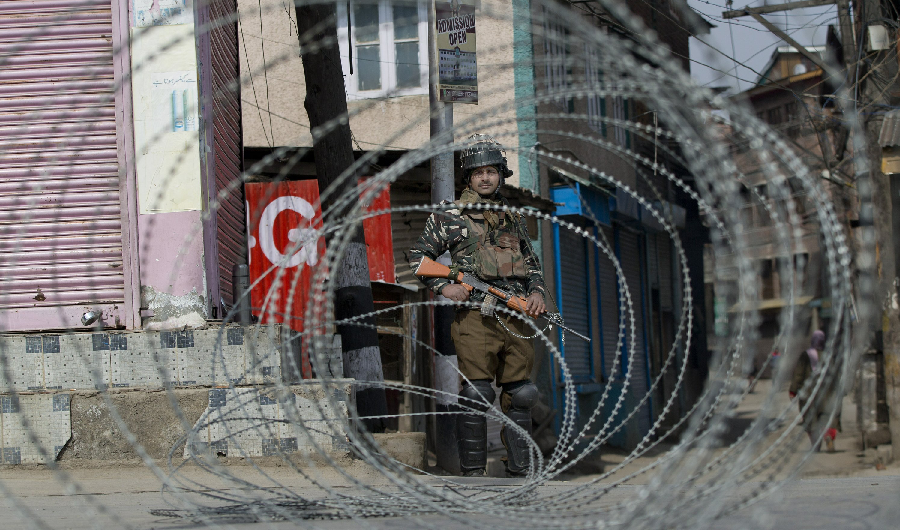 An Indian paramilitary soldier is seen through barbed wire as he stands guard during security lockdown in Srinagar, Indian controlled Kashmir, Sunday, Feb. 24, 2019. (AP)