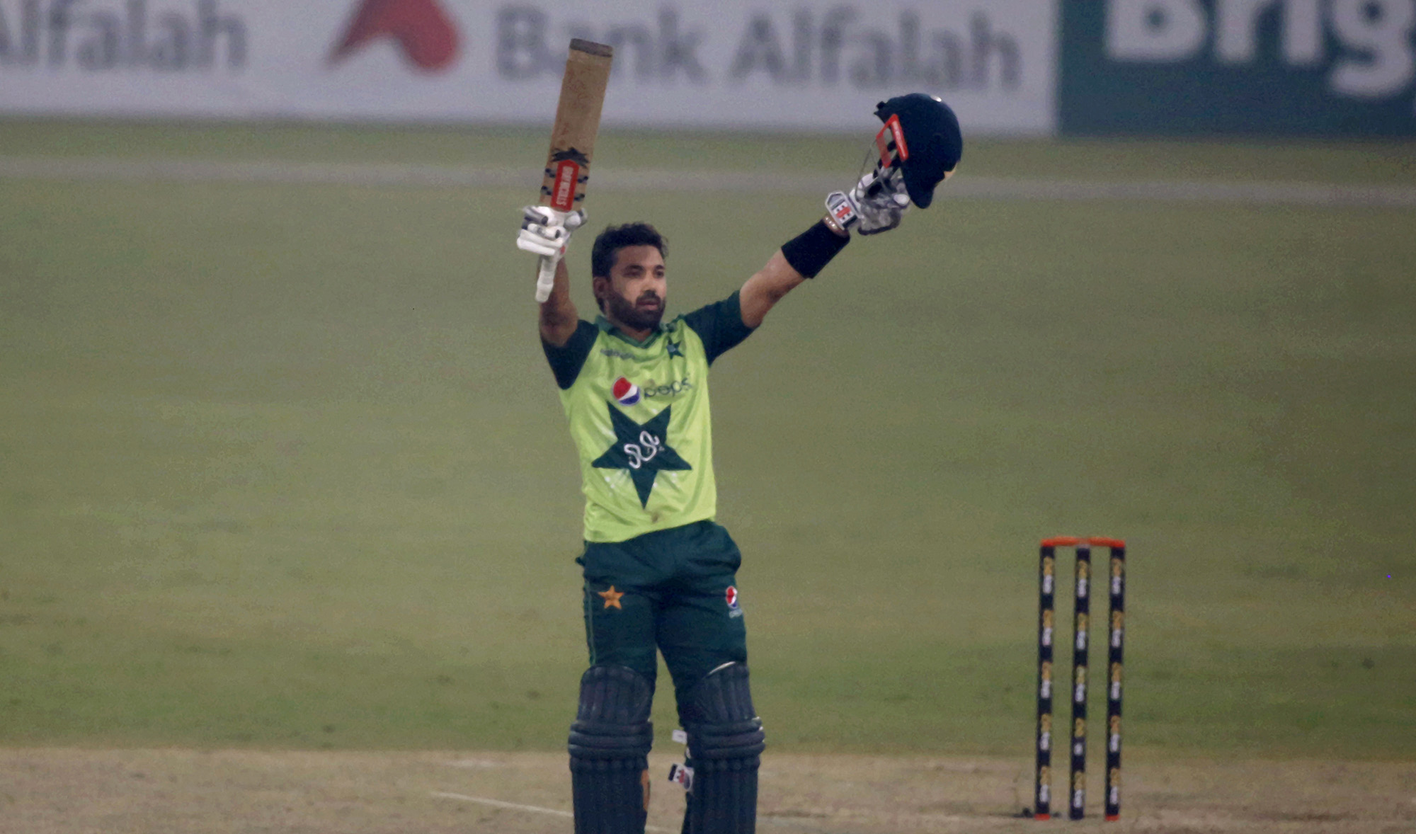 Pakistan's Mohammad Rizwan raises bat and helmet to celebrate his century during the 1st Twenty20 cricket match between Pakistan and South Africa at the Gaddafi Stadium, in Lahore, Pakistan on February 11, 2021. (AP)