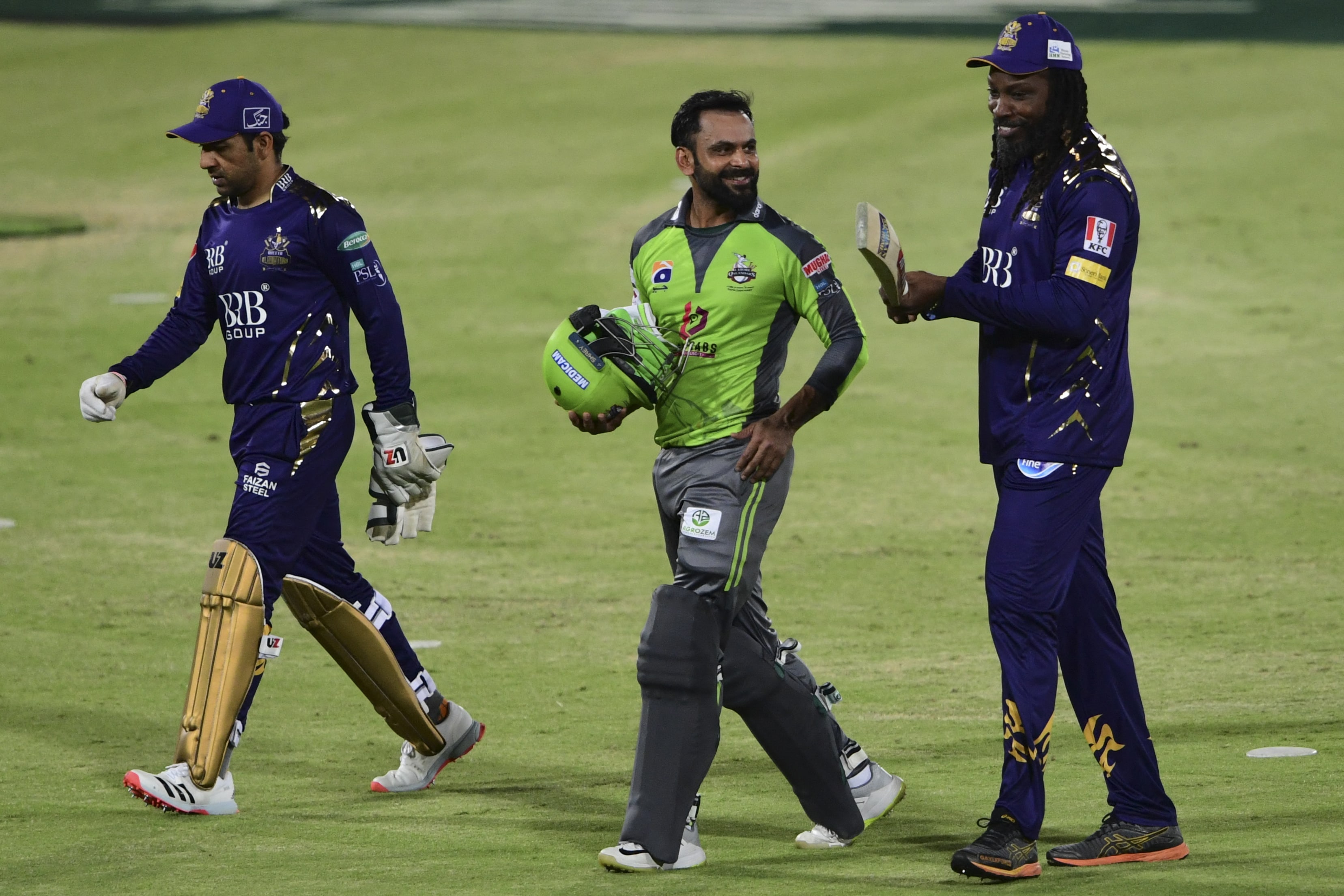 Lahore Qalandars' Mohammad Hafeez (C) walks back to pavilion with Quetta Gladiators's players Sarfraz Ahmed (L) and Chris Gayle (R) after Lahore's victory during the Pakistan Super League (PSL) T20 cricket match between Lahore Qalandars and Quetta Gladiators at the National Stadium in Karachi on February 22, 2021. (AFP)