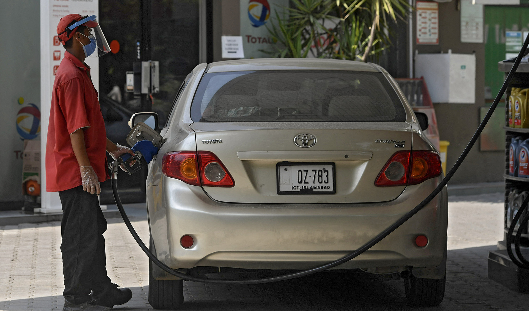 An employee wearing a face shield and mask as a precautionary measure against the spreading COVID-19 coronavirus fills the tank of a car at a petrol station in Islamabad, Pakistan on July 9, 2020. (AFP/File)