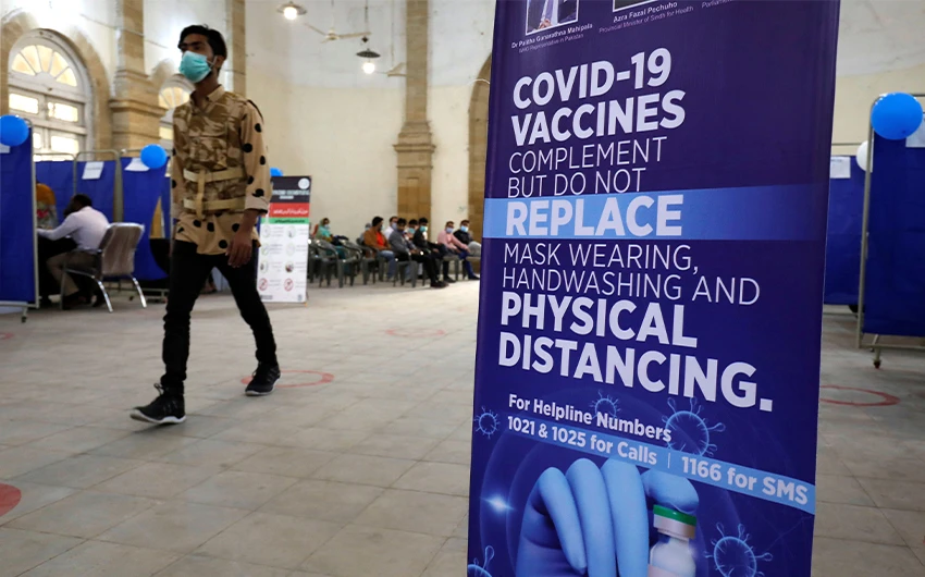 A man walks past an awareness sign inside the Khaliq Dina Hall and Library, which has been converted to be used as a vaccination centre, to administering coronavirus disease (COVID-19) vaccine, in Karachi, Pakistan February 1, 2021. (REUTERS)