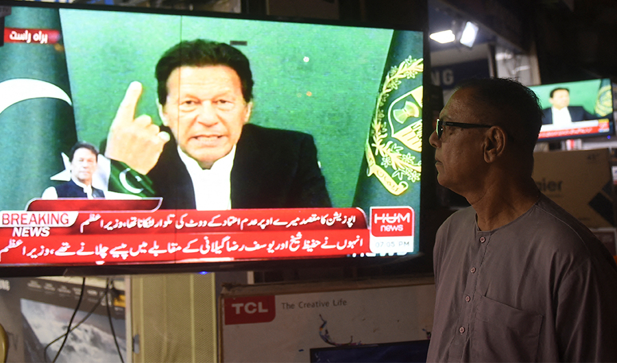 A bystander listens Pakistan's Prime Minister Imran Khan addressing the nation on television, in Karachi on March 4, 2021, after Foreign Minister Shah Mahmood Qureshi announced that Khan would seek a confidence vote in the National Assembly. (AFP)