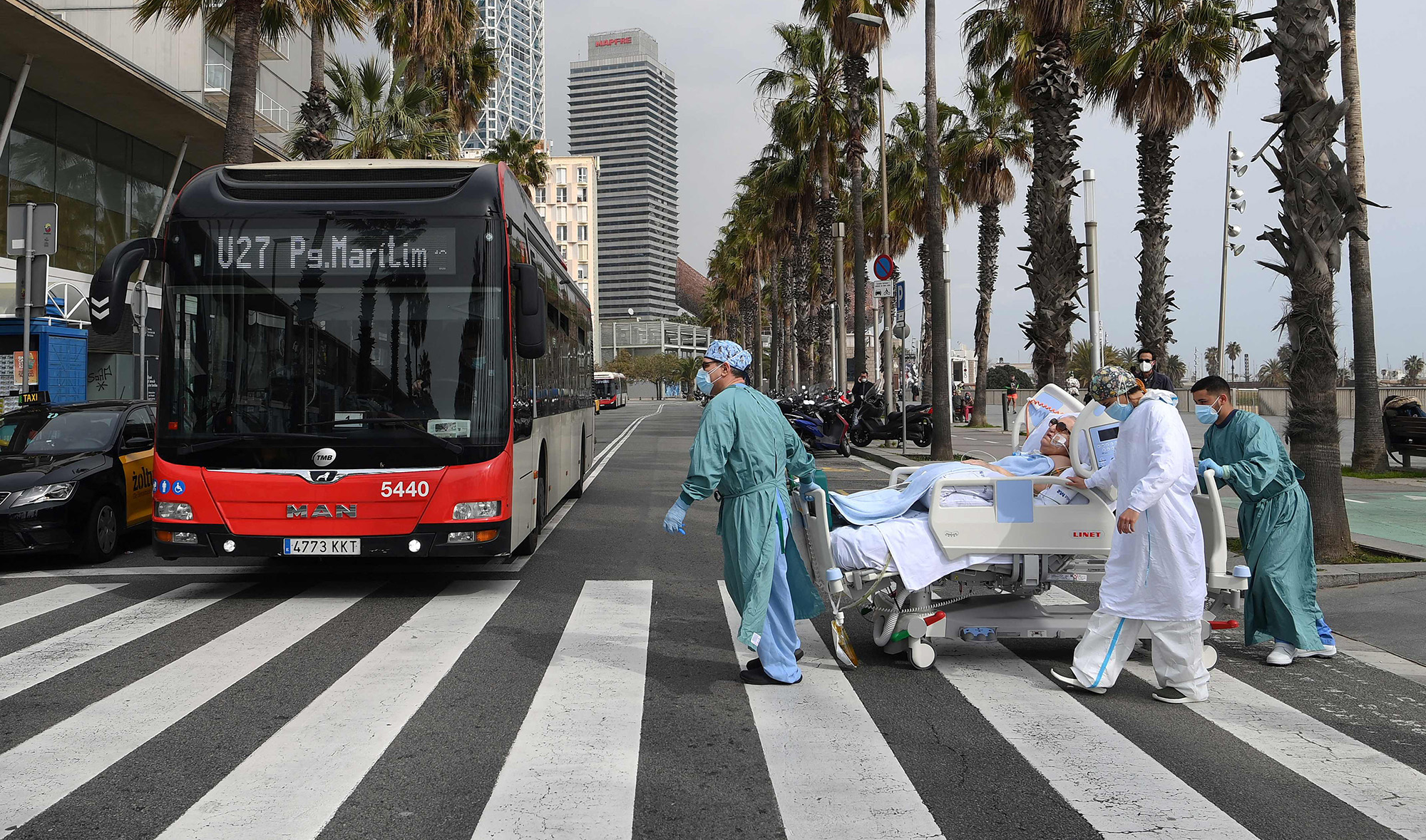 Medical personnel of Hospital del Mar take COVID-19 patient, Marta Pascual, 72, back to the hospital after getting some fresh air by the sea, at the Barceloneta beach esplanade in Barcelona on March 4, 2021. (AFP)