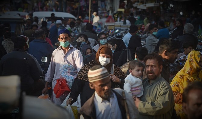 Shoppers wearing facemasks as a preventive measure against the Covid-19 coronavirus walk through a market in Karachi on November 26, 2020. (AFP)