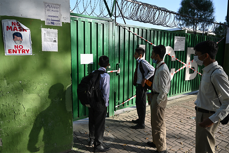 Students read a notice hanging on a school gate sealed by authorities in Islamabad on October 5, 2020. (AFP)