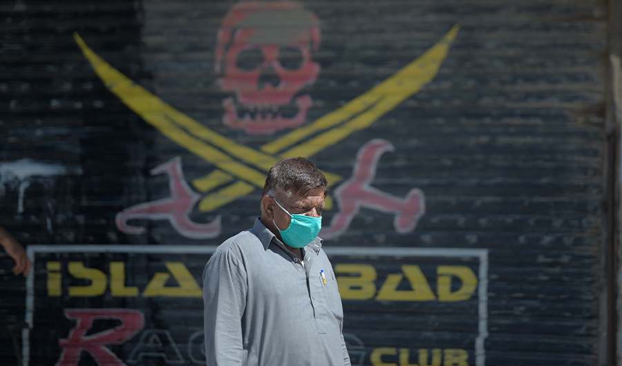 A Pakistani man wearing a facemask walks past a closed shop of a market area in Karachi on March 22, 2020. (AFP)