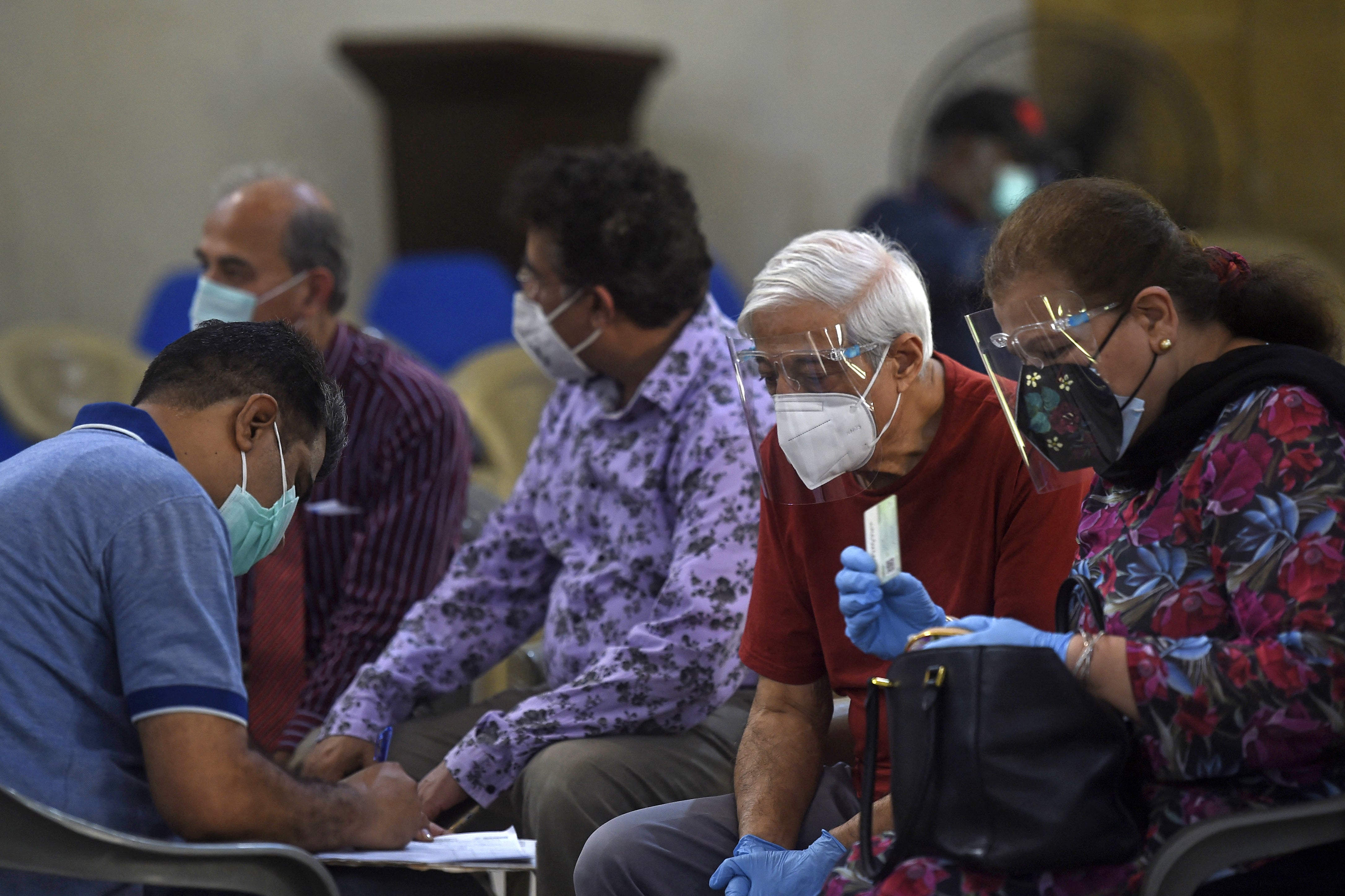 A medical worker jots down the details of senior citizens awaiting to get inoculated with the Covid-19 coronavirus vaccine at a vaccination center in Karachi on March 16, 2021. (AFP)