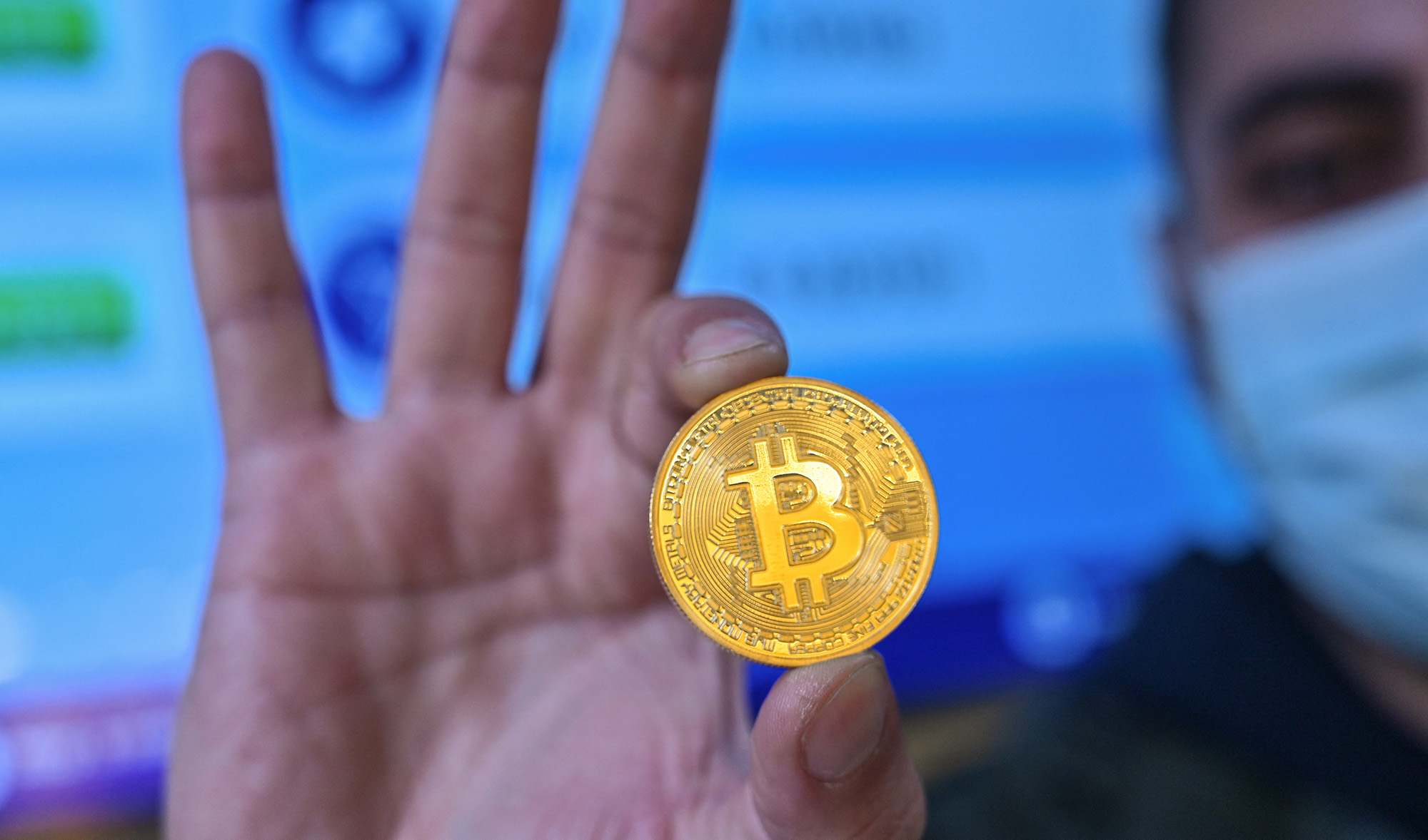 This photograph taken on December 17, 2020 shows a man holding a physical imitation of a Bitcoin at a crypto currency "Bitcoin Change" shop, near the Grand Bazaar, in Istanbul. (AFP/File)