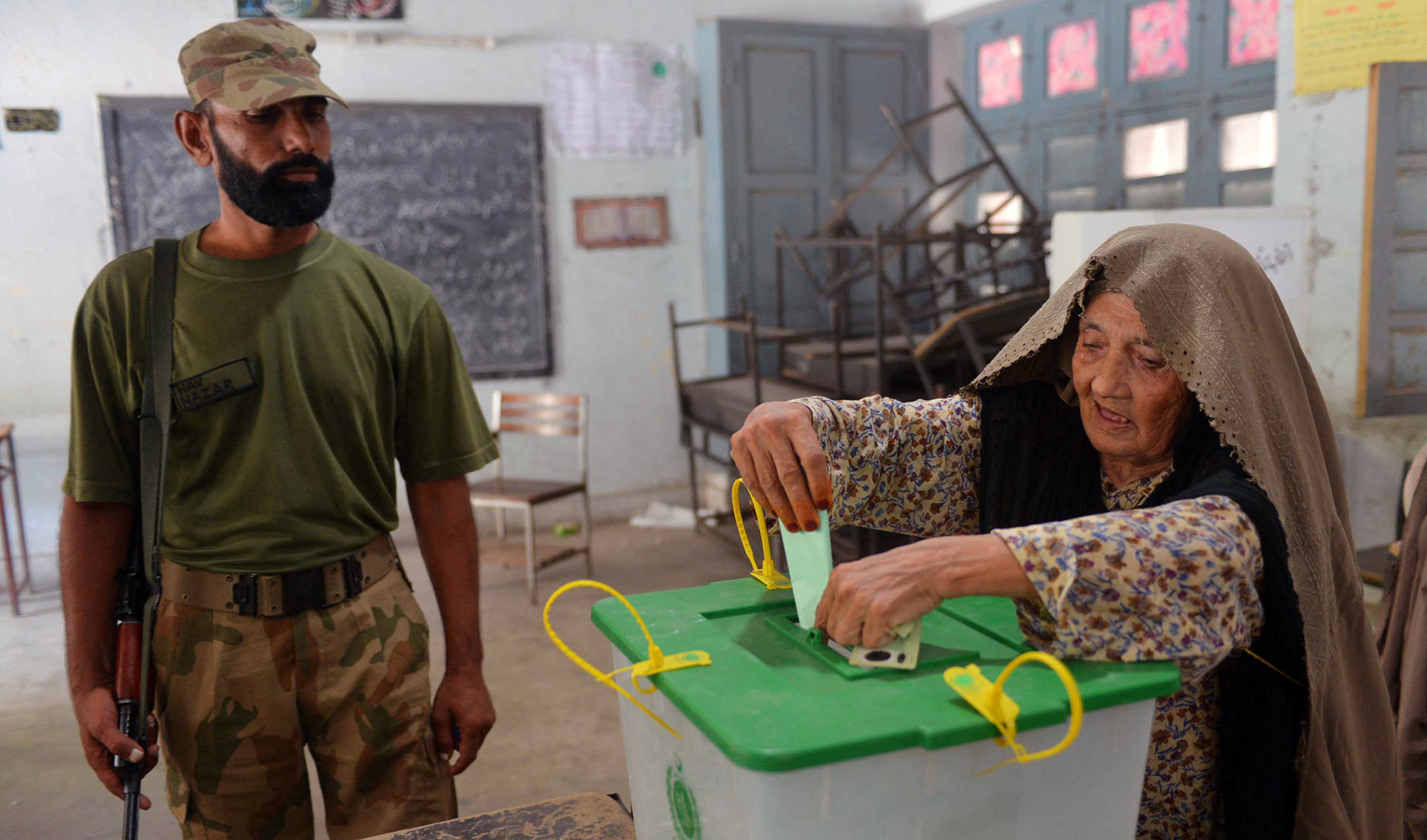 Pakistani soldier watches a voter cast her ballot during the country's by-election in several constituencies, in Peshawar on August 22, 2013. (AFP/File)