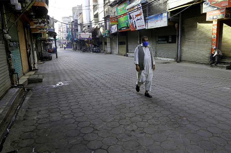 A lone man walks past shops closed due to the new government instructions to control the spread of the coronavirus in Peshawar, Pakistan on March 20, 2021. (AP)