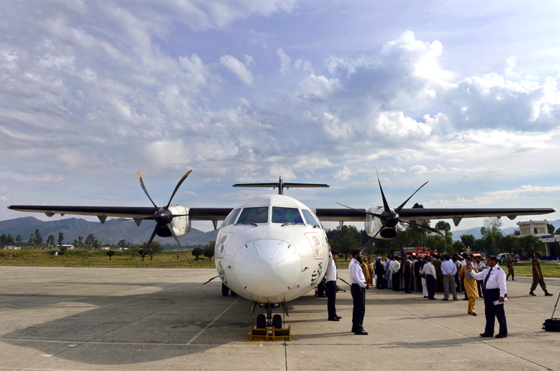Pakistan International Airline (PIA) officials and media representatives gather around a plane after it arrived in Saidu Sharif in the Swat Valley on October 10, 2012. (AFP/File)