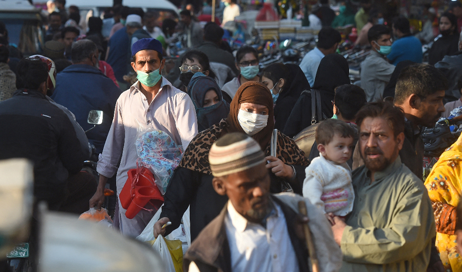 Shoppers wearing facemasks as a preventive measure against the Covid-19 coronavirus walk through a market in Karachi on November 26, 2020. (AFP)