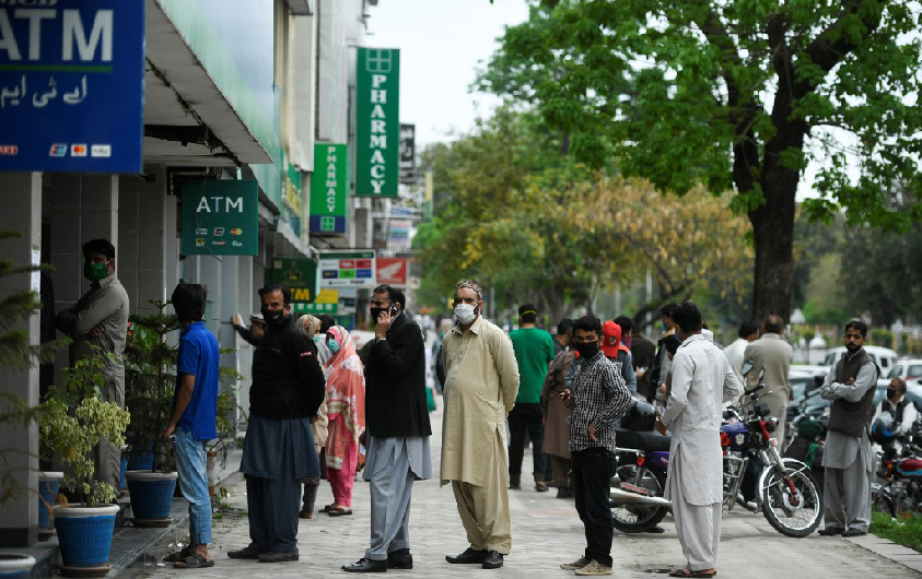 Residents wearing facemasks wait for their turn to withdraw money outside a bank in Islamabad on March 30, 2020. (AFP/File)