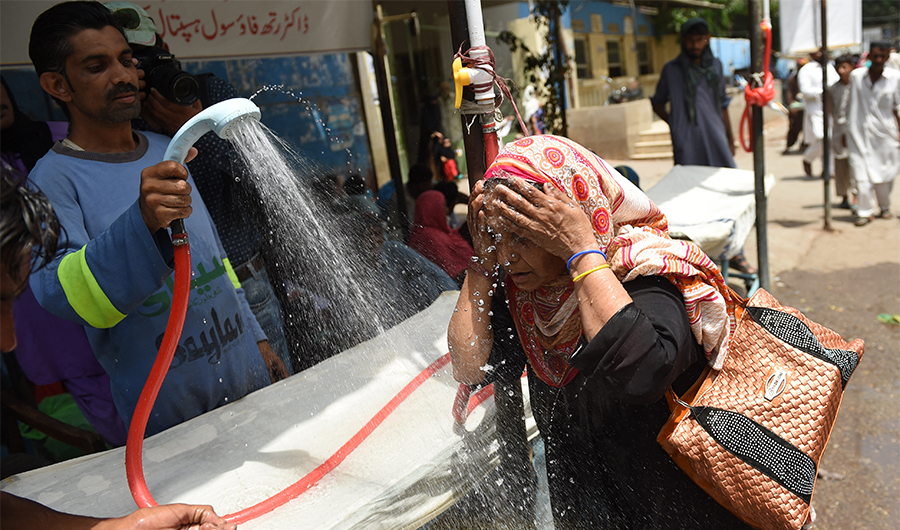 A Pakistani volunteer showers a woman with water during a heatwave in Karachi, Pakistan, on May 29, 2018. (AFP/File)