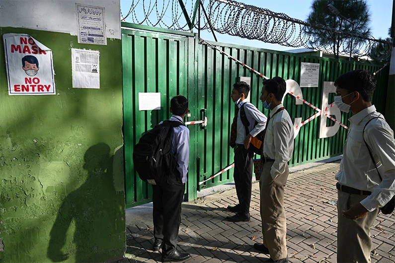 Students read a notice hanging on a school gate sealed by authorities in Islamabad on October 5, 2020. (AFP)