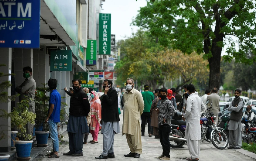 Residents wearing facemasks wait for their turn to withdraw money outside a bank in Islamabad on March 30, 2020. (AFP/File)