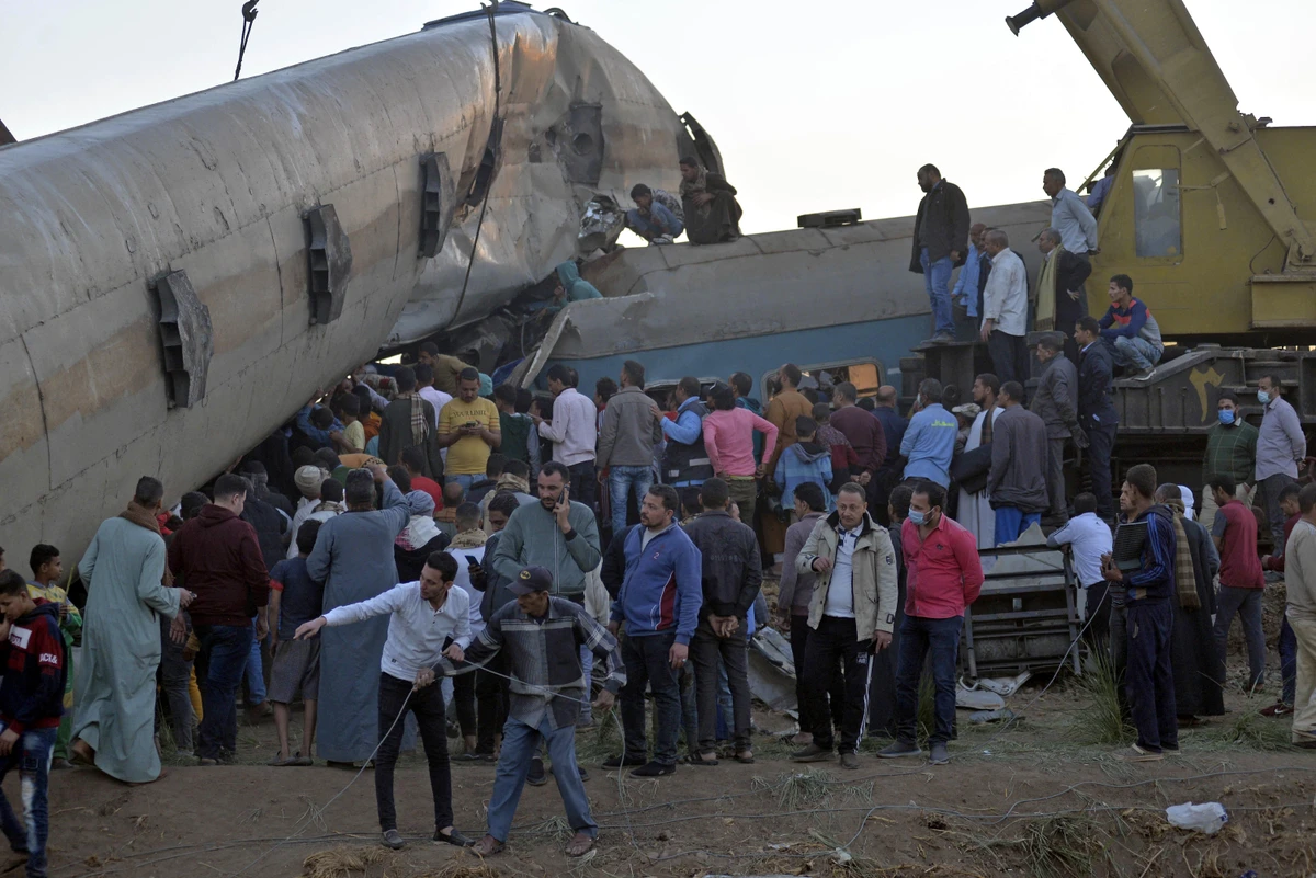 People gather around the wreckage of two trains that collided in the Tahta district of Sohag province, some 460 kilometres (285 miles) south of the Egyptian capital Cairo, reportedly killing at least 32 people and injuring scores of others, on March 26, 2021. (AFP)