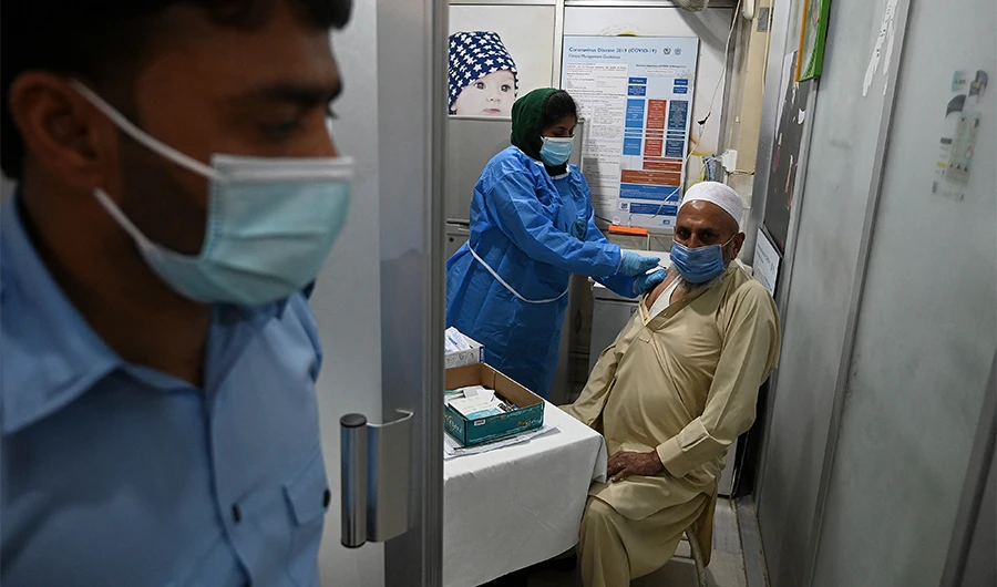 A senior citizen (R) receives a dose of the Chinese-made Sinopharm vaccine against the Covid-19 coronavirus, at a vaccination centre in Islamabad, Pakistan, on March 30, 2021. (AFP)