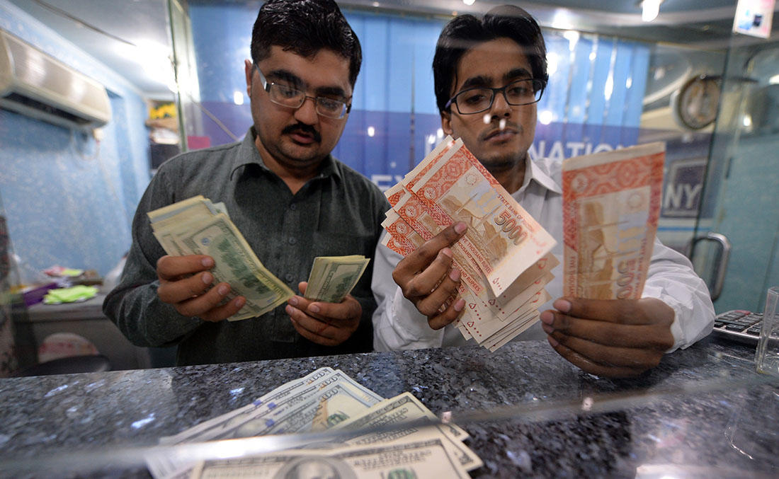 Money dealers count Pakistani rupees, right, and US dollars at a currency exchange in Islamabad. Pakistan, on March 12, 2014. (AFP/File)