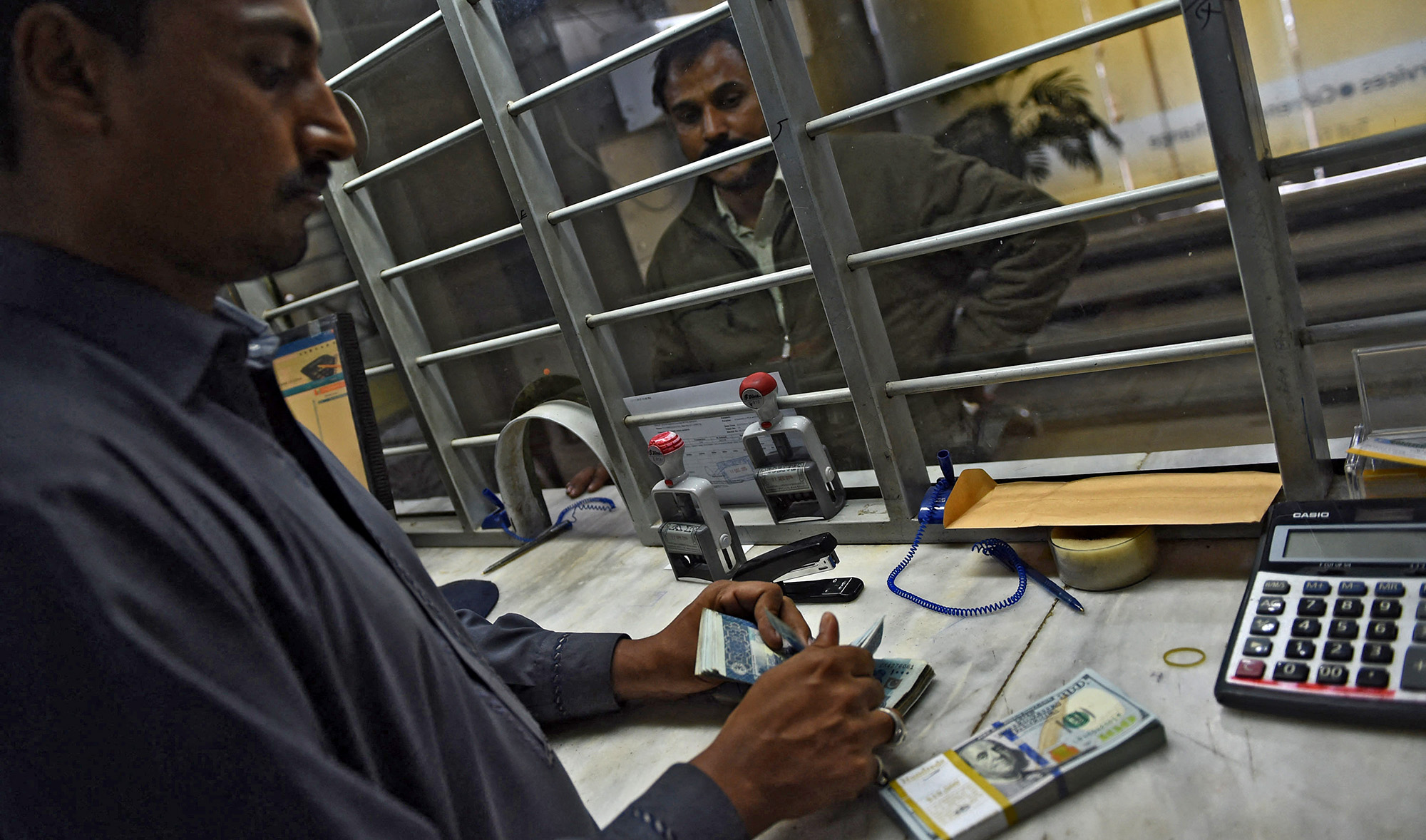 A Pakistani currency dealer counts rupees and US dollars at a currency exchange in Karachi, Pakistan, on December 17, 2015. (AFP/File)