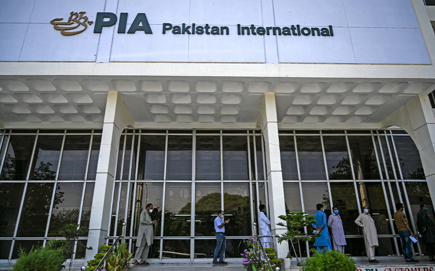 People stand in queue as they wait their turn to buy flight tickets outside Pakistan International Airlines (PIA) office in Islamabad on July 1, 2020. (AFP/File)