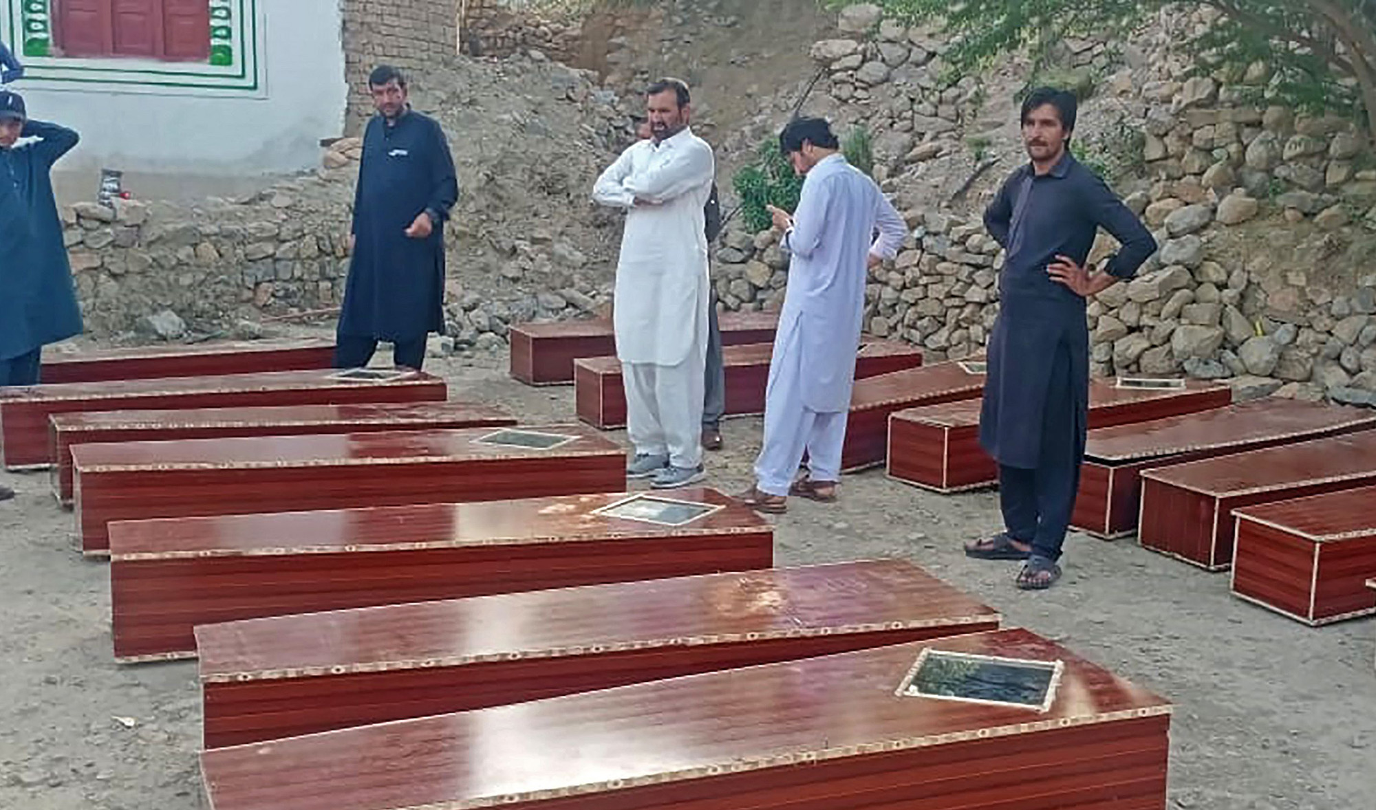 Men stand beside the empty caskets as they wait to receive the decomposed bodies of miners who went missing nearly a decade ago in northwestern Pakistan that have been found in a mass grave, on the outskirts of Peshawar on April 9, 2021. (AFP)