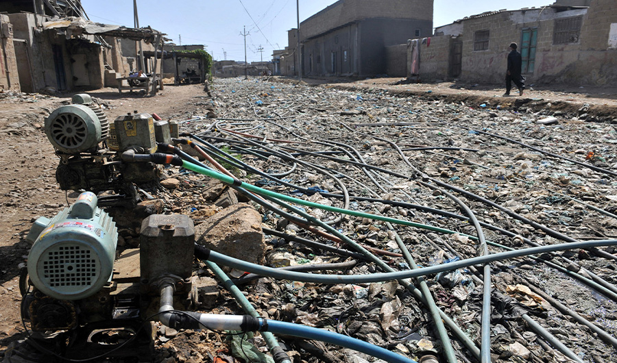 A Pakistani resident walks past pumps affixed to a network of pipes placed above garbage and drains to get water supplies in a slum area of Karachi on April 22, 2010. (AFP/ File)