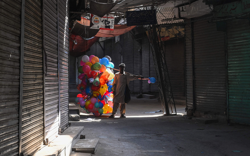 A balloon vendor walks past a shuttered market in Lahore, Pakistan, on April 11, 2021, as a lockdown was imposed to control the spread of the Covid-19. (AFP)