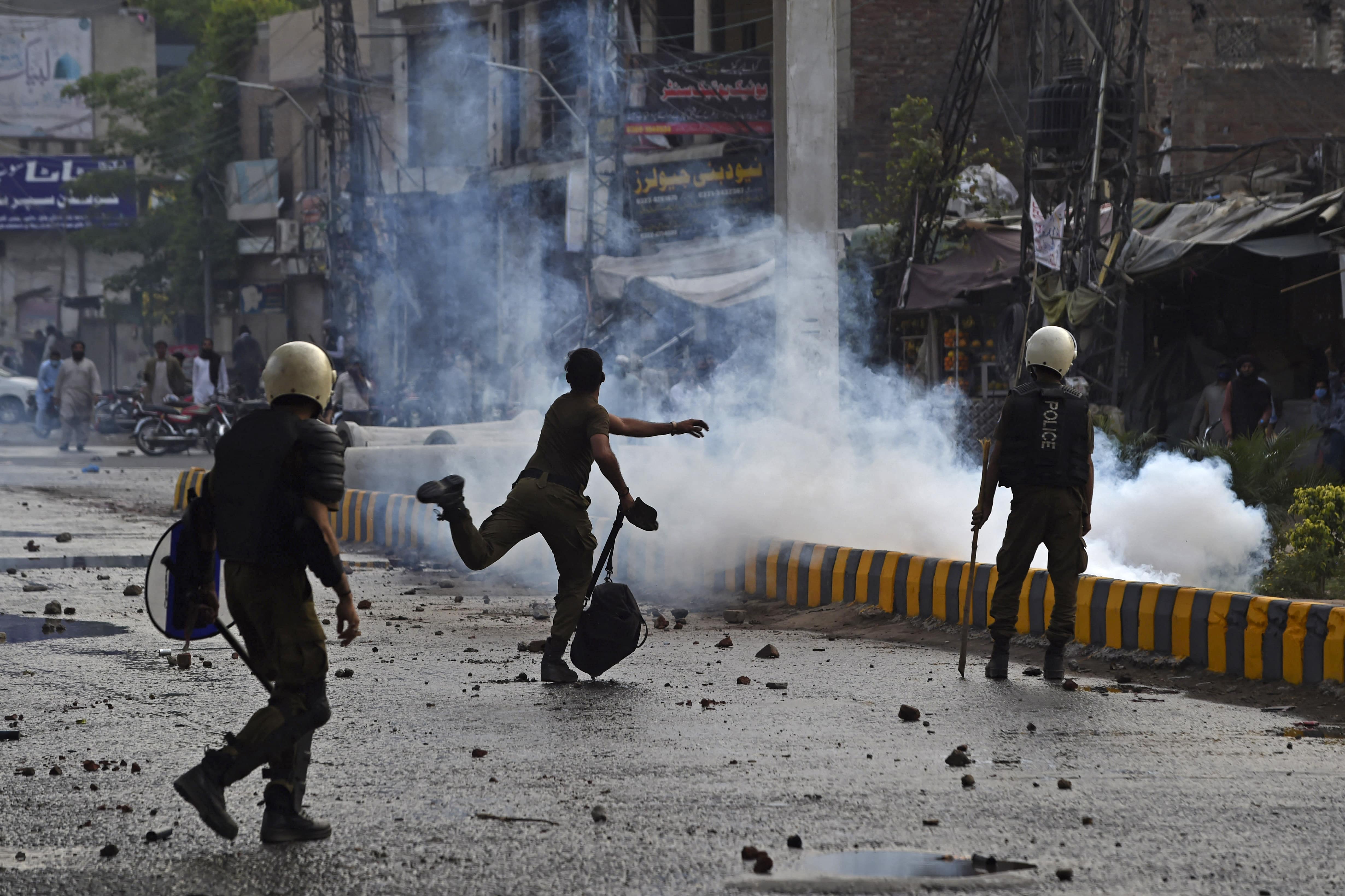 A policeman throws a stone towards supporters of Tehreek-e-Labbaik Pakistan (TLP) during a protest in Lahore on April 12, 2021, after the arrest of their leader, who has called for the expulsion of the French ambassador. (AFP)