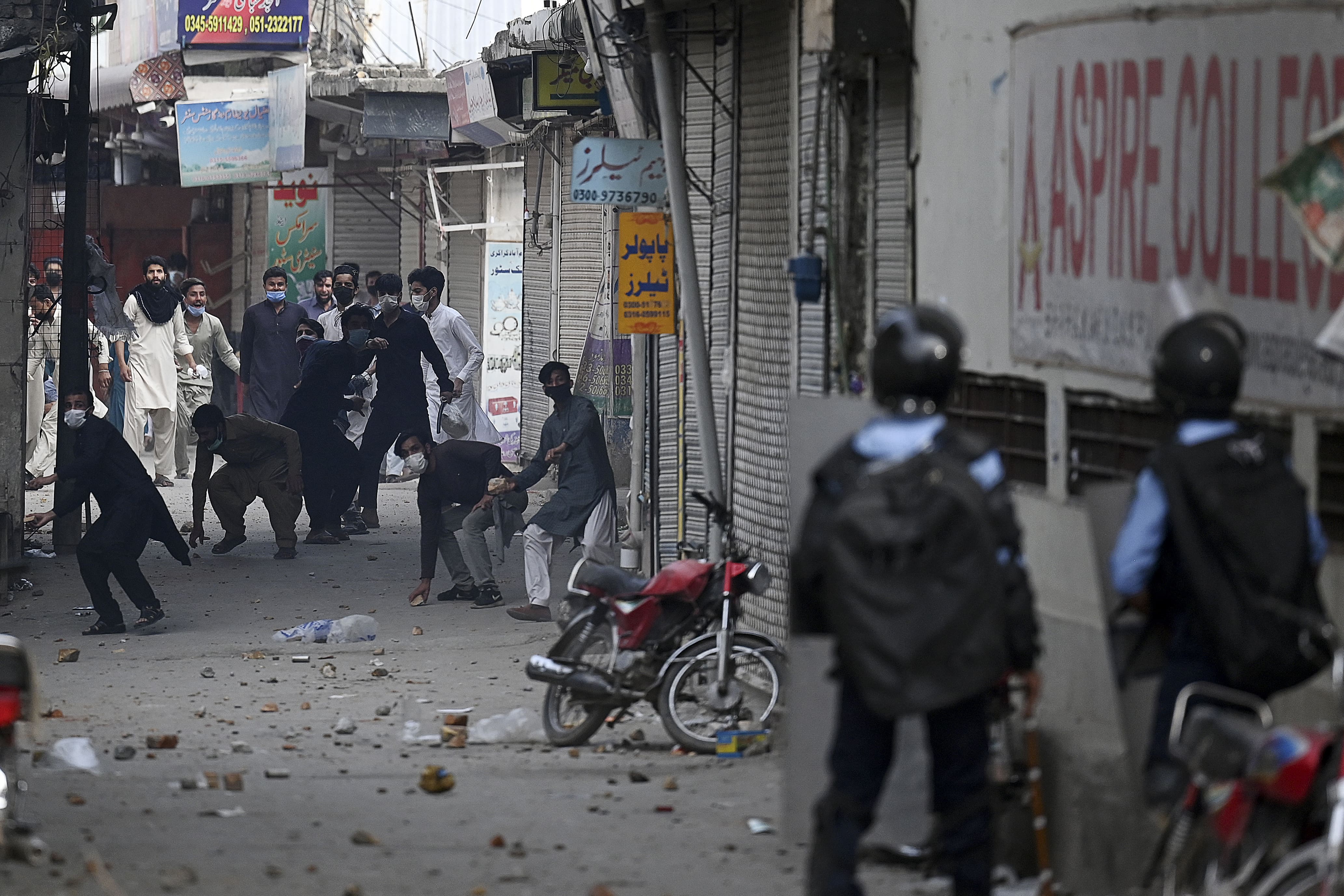 Supporters of Tehreek-e-Labbaik Pakistan (TLP) party throw stones towards riot policemen during a protest against the arrest of their leader as he was demanding the expulsion of the French ambassador over depictions of Prophet Muhammad, in Barakahu neighbourhood of Islamabad on April 13, 2021. (AFP)