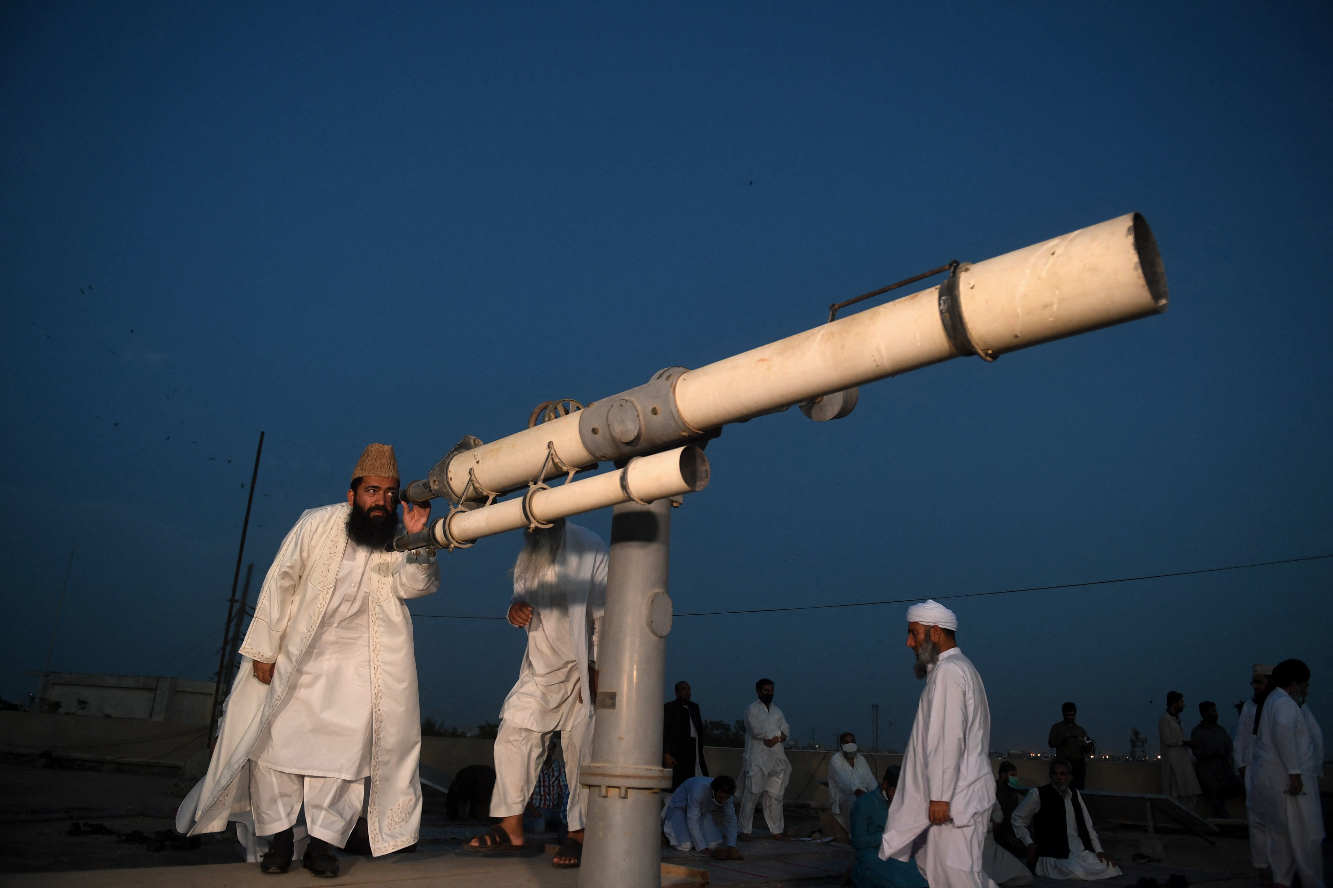 Maulana Abdul Khabeer Azad (L), a member of Pakistan Ramadan moon-sighting committee, looks through a telescope for the new moon that signals the start of the Muslim fasting month of Ramadan in Karachi on April 23, 2020. (AFP/File)
