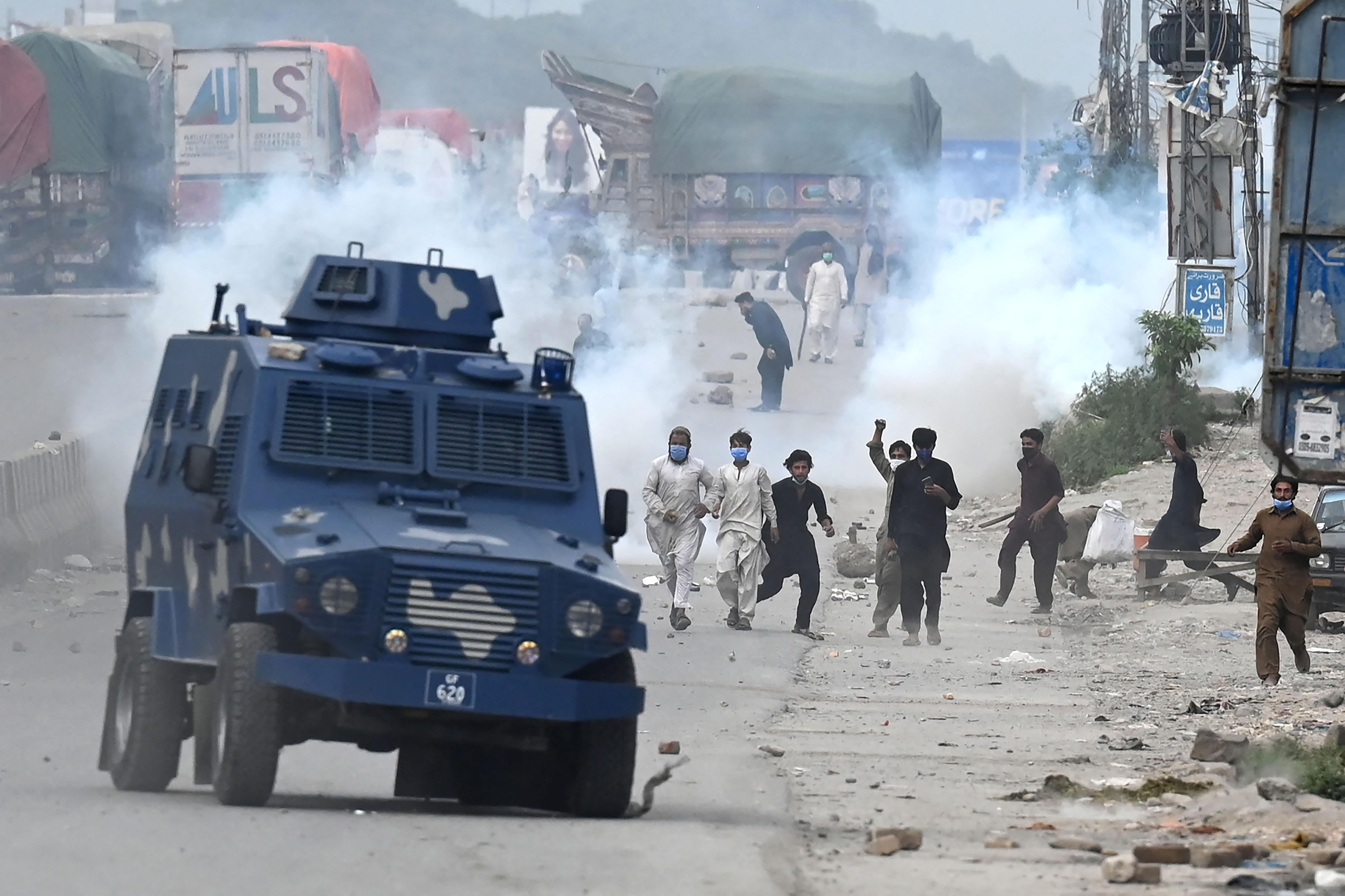 Supporters of Tehreek-e-Labbaik Pakistan (TLP) party throw stones over the police armoured vehicle during a protest against the arrest of their leader as he was demanding the expulsion of the French ambassador over depictions of Prophet Muhammad, in Barakahu neighbourhood of Islamabad on April 13, 2021. (AFP)