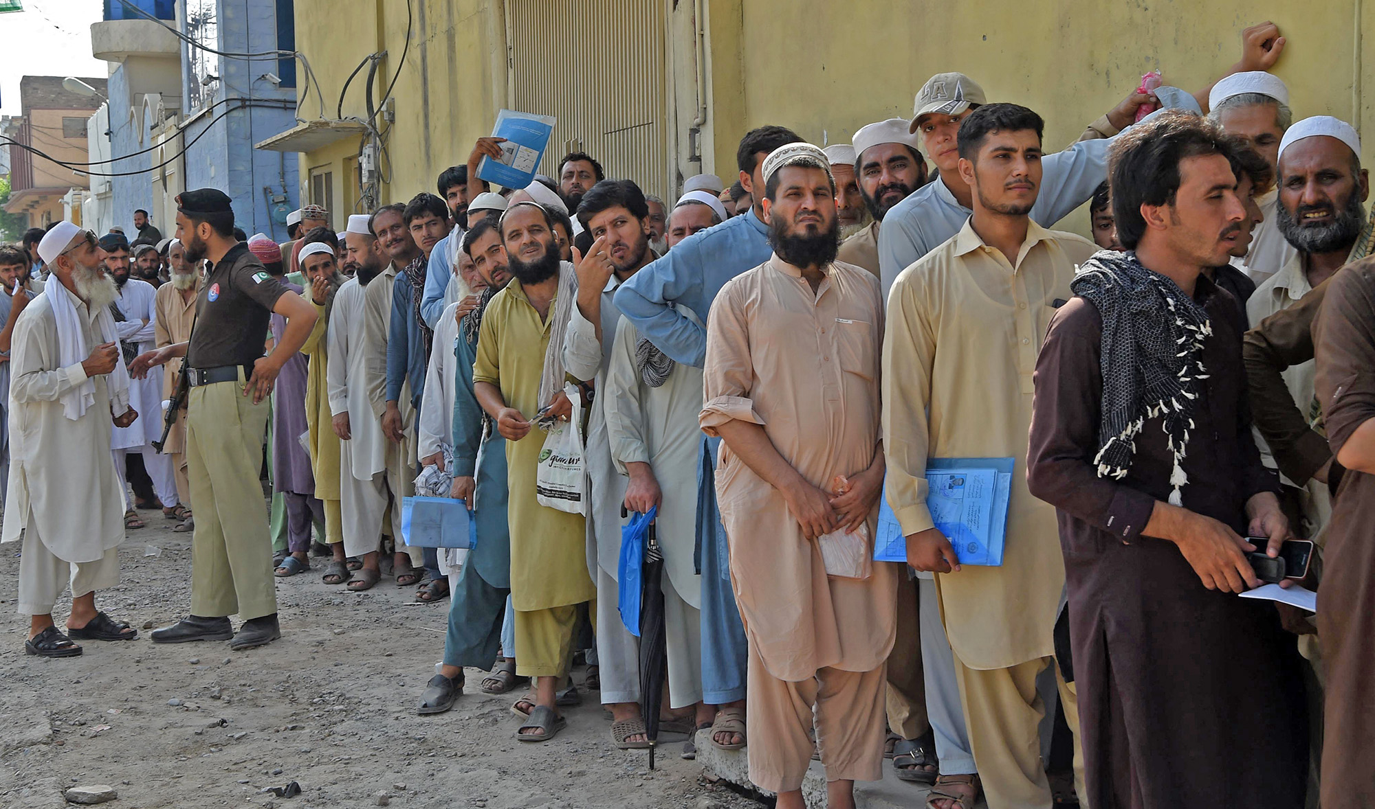 Afghan refugees wait for their turn outside a Pakistani registration center in Peshawar, Pakistan, on August 17, 2017. (AFP/File)