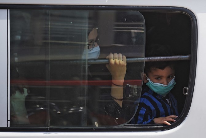 A mother and son wearing facemask sit in a local transport outside a bus station in Islamabad on April 10, 2021 after the government restricted intercity public transport for two days in a week to control spread of Covid-19 coronavirus. (AFP / File photo)