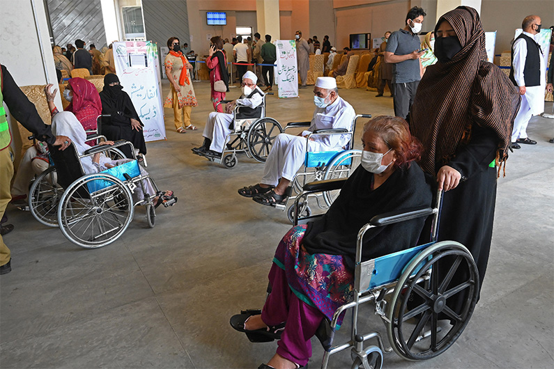 Senior citizens on wheelchairs WAIT inside an Expo Centre in Lahore on April 1, 2021. (AFP)