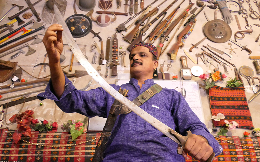 Javed Bangulzai holds an ancient sword in front of the artifact collection inside his home in Quetta, Pakistan on April 20, 2021. (AN Photo)