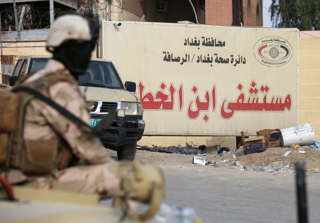 Members of Iraqi security forces stand at the gate of Ibn Al-Khatib Hospital in Baghdad, on April 25, 2021, after a fire erupted in the medical facility reserved for the most severe COVID-19 cases. (AFP)
