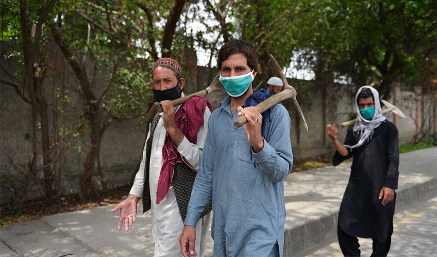 Pakistani labourers wearing facemask walks along a street during in Rawalpindi on April 14, 2020. (AFP)