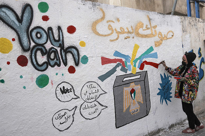 A Palestinian artist adds the final touches to a mural painting calling on people to vote during the upcoming elections (legislative in May and presidential in July) in a street in Gaza City, on March 24, 2021. (AFP photo)